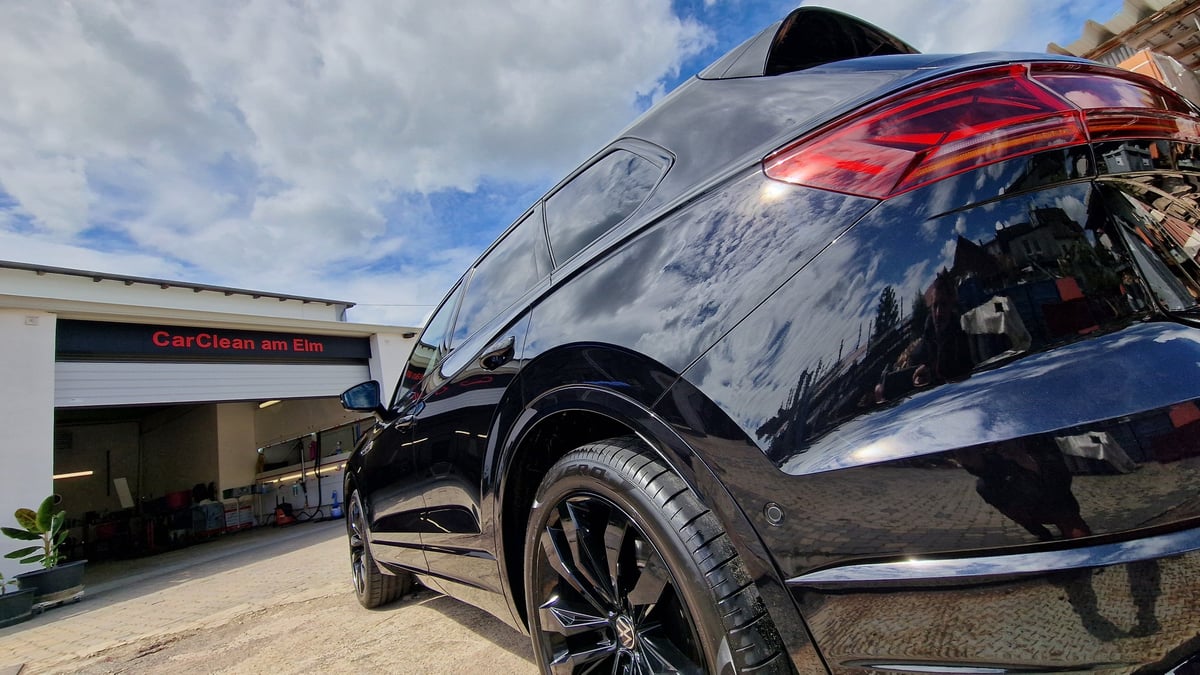 Black SUV with open hood displayed in front of a car service center building