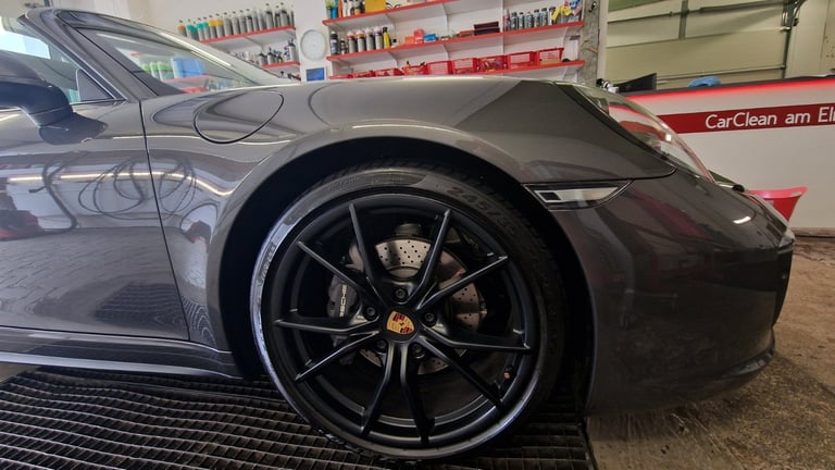 Black sports car with black alloy wheels in a car wash bay, showing the side profile and wheel detail