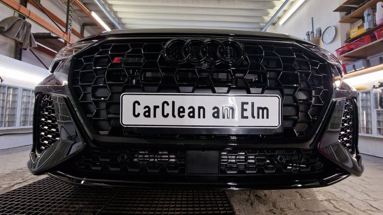 Black car front view in car wash facility with CarClean am Elm sign on license plate area