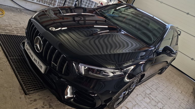 Black Mercedes-Benz SUV parked indoors with hood open, showing the engine compartment and front grille detail